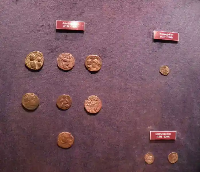 Coins with designs including a six-pointed star, face, and different scenes, located at Archaeological Museum of Izmir, Turkey